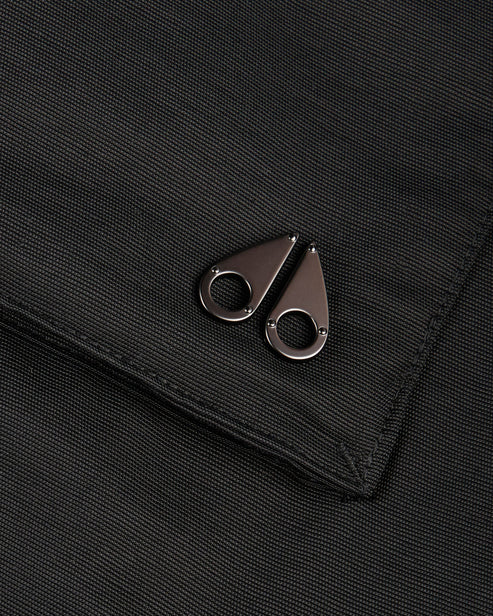 Close-up of a matte, dark gray fabric with two teardrop-shaped metal accents, each having a circular cutout.