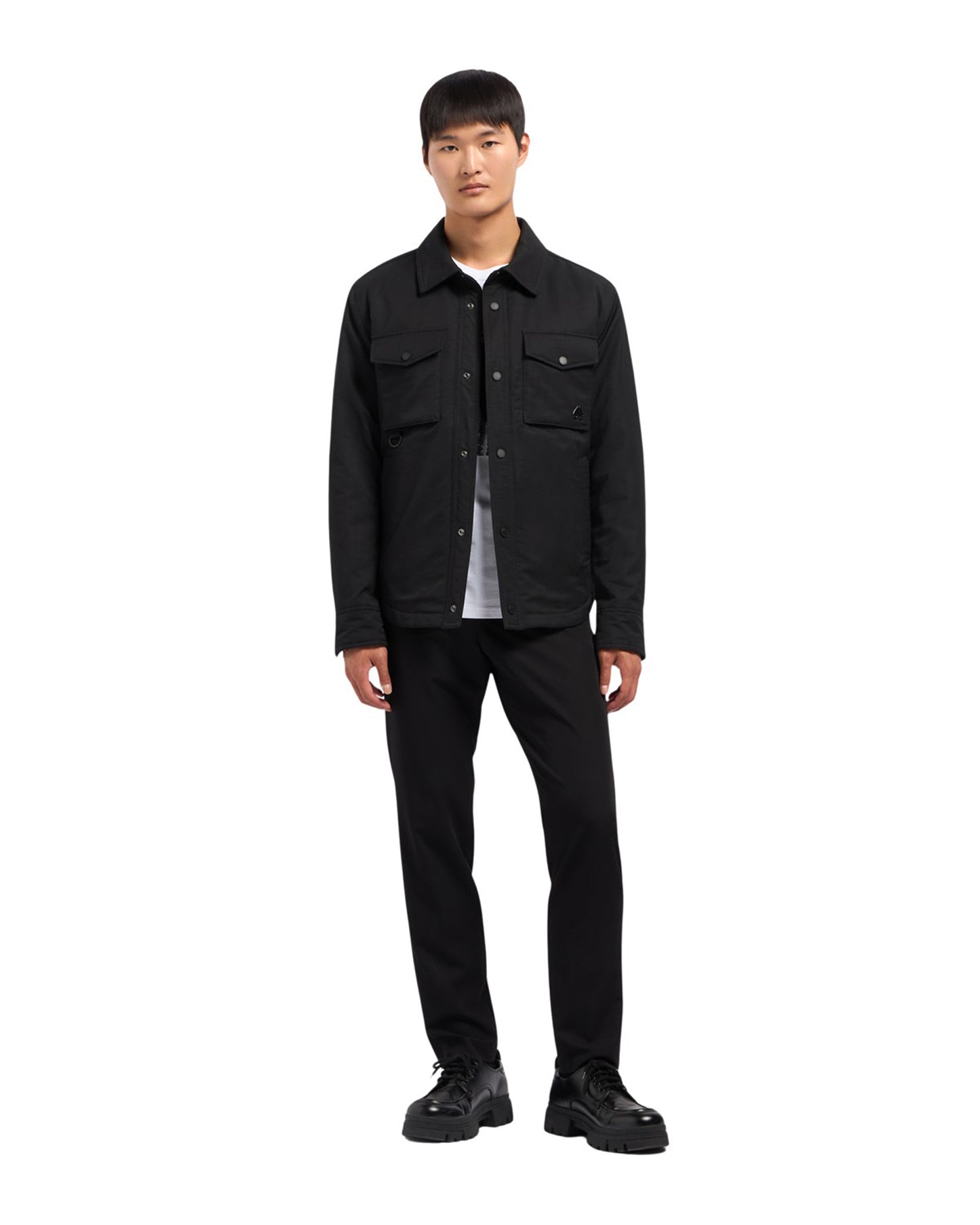 A man wearing a black button-down shirt, black pants, and black shoes.