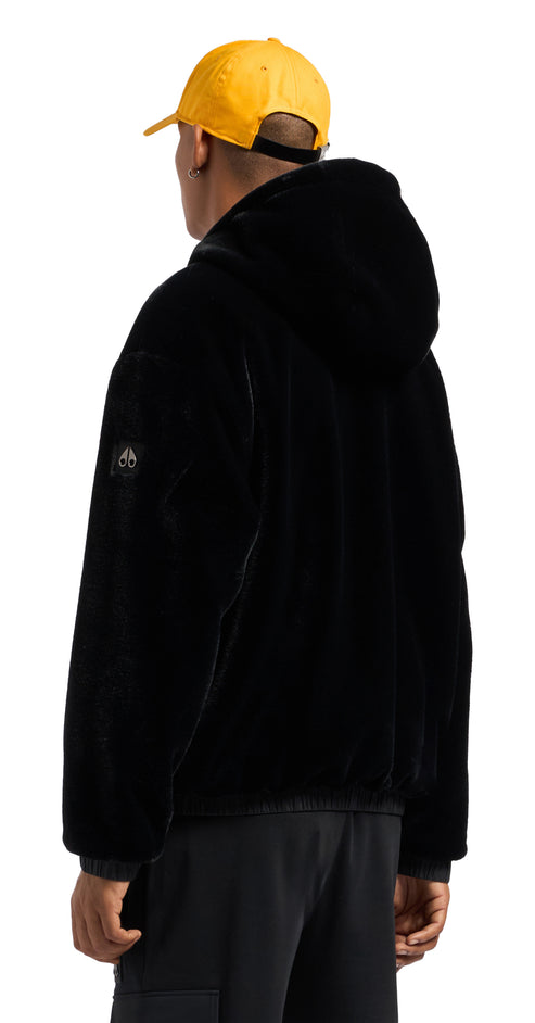 A person in black jacket with hood and yellow hat from the back.