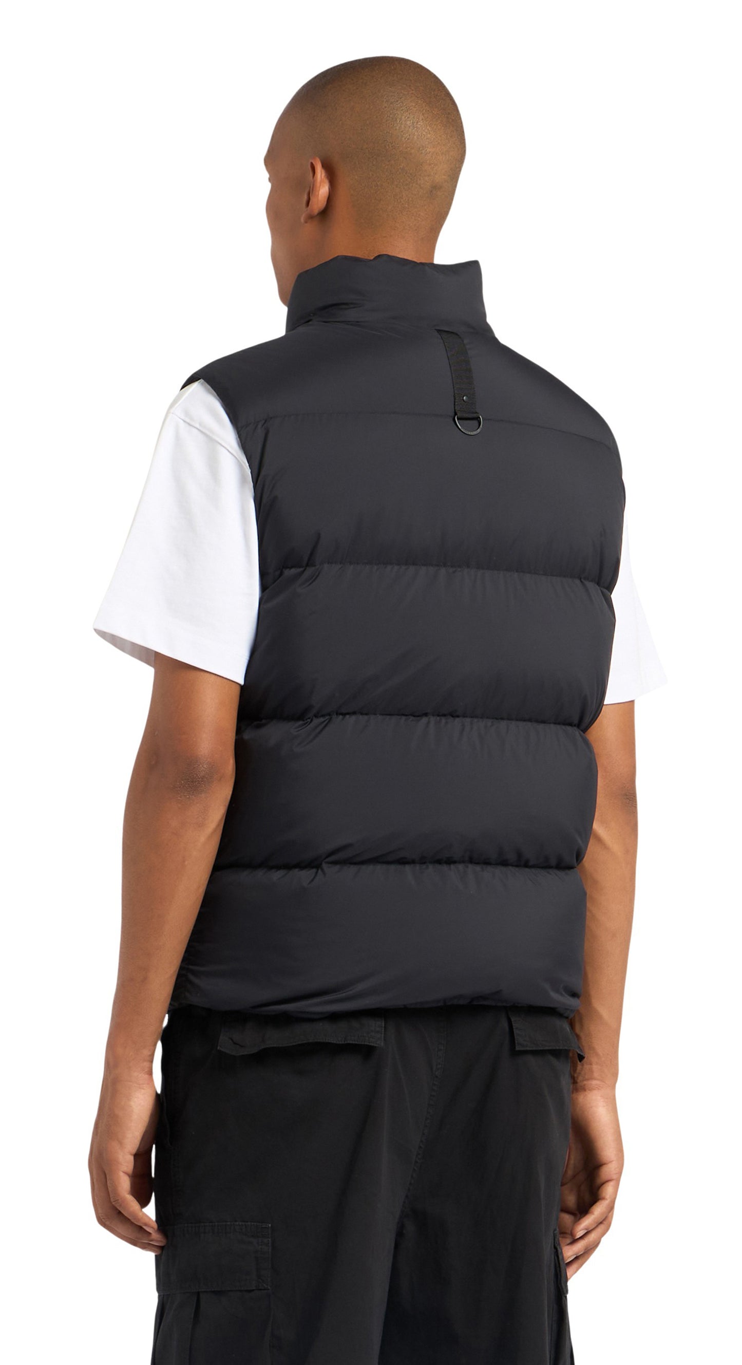 A Black puffer vest on a person wearing a white t-shirt and black pants; rear view.