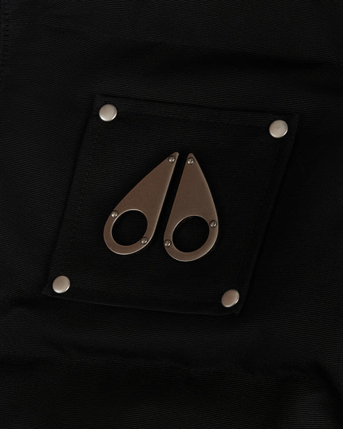 Black patch with metal logo resembling two teardrops, secured with four silver rivets.