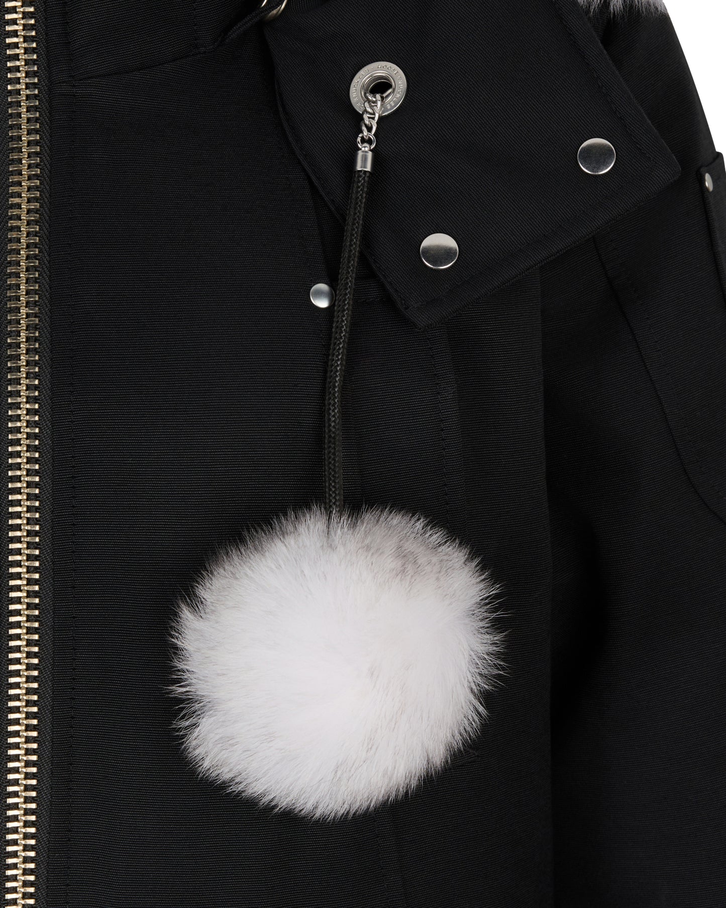 Close-up of a black coat with a detachable white fur pom-pom attached to the hood.