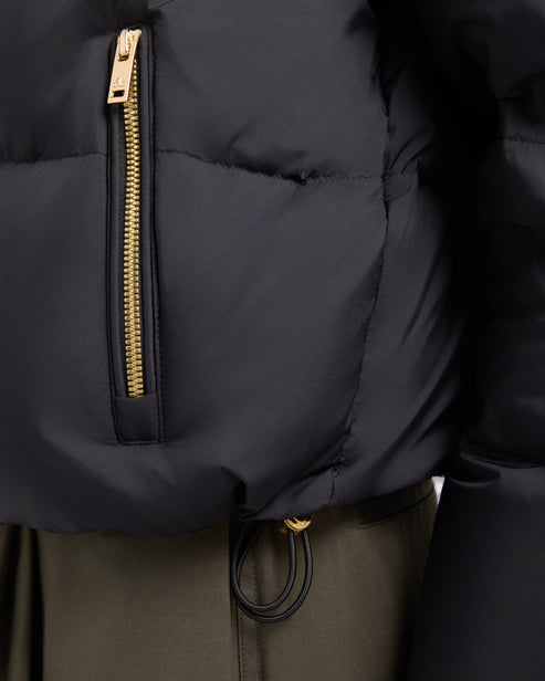 Close-up of a black puffer jacket with gold zipper and drawstring.