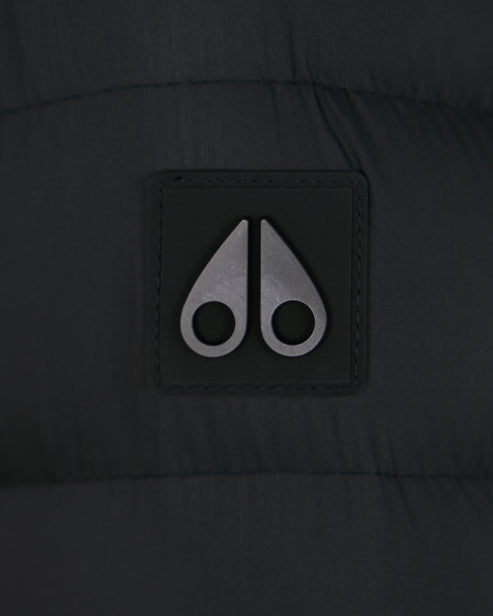 Close-up of a gray logo with two curved metal shapes resembling moose knuckles, stitched onto dark fabric.