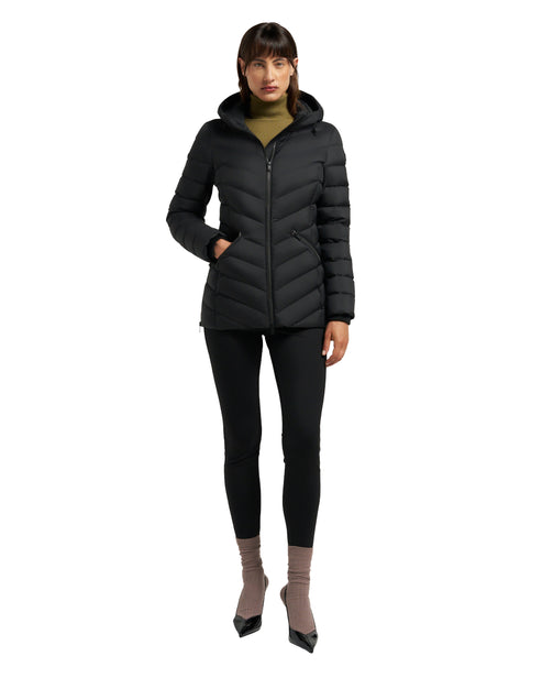 A person wearing a black, hooded puffer jacket, black leggings and brown heels.