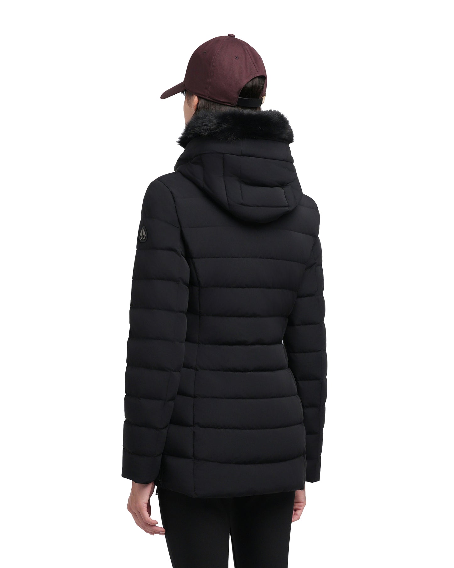 Back view of a black puffer coat with a hood and faux fur trim, worn by a person with a maroon baseball cap.