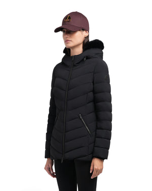 A woman wearing a black puffy jacket with a fur-trimmed hood and a maroon baseball cap.