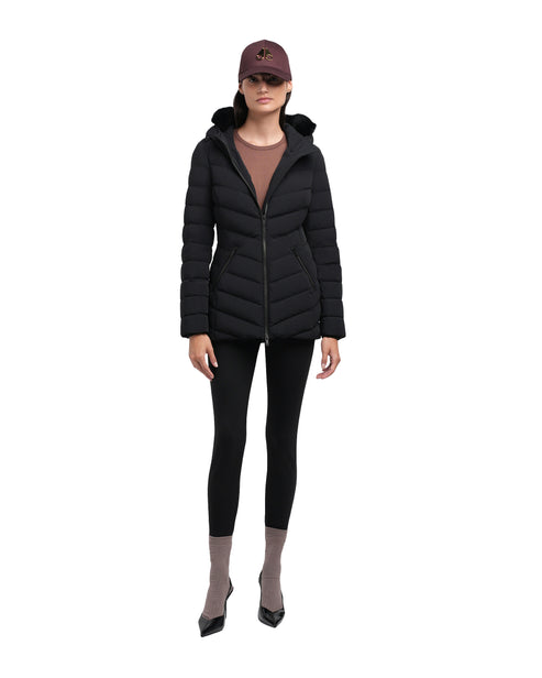 Woman wearing a black quilted hooded puffer jacket, black leggings, taupe socks, and black heels.