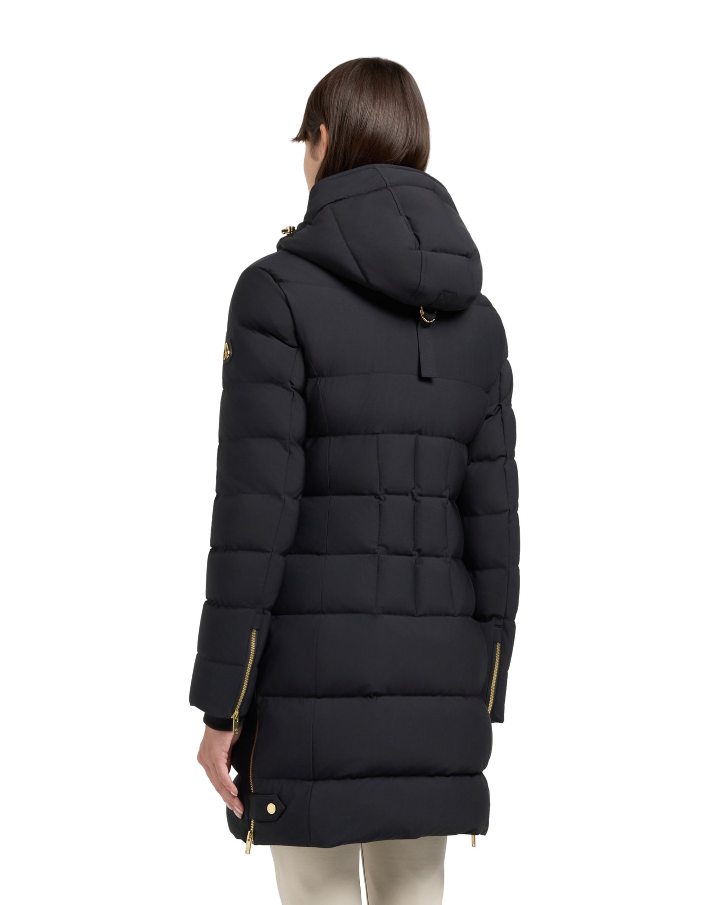 Back view of a woman wearing a black quilted parka with a hood and gold zippers.
