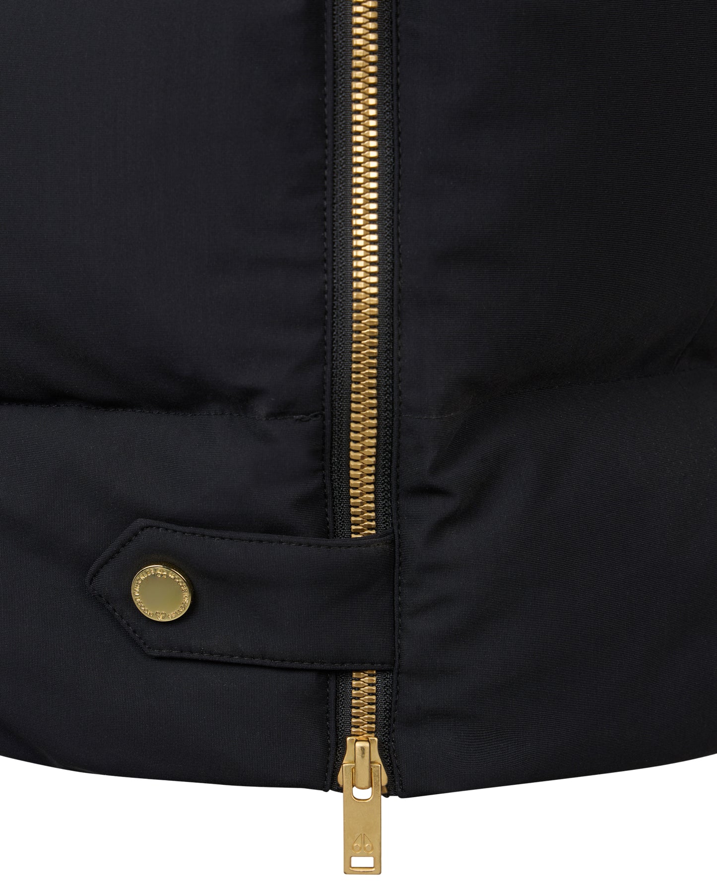 Close-up of a black garment with a gold zipper and gold button.