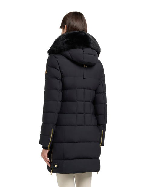 Back view of a long black puffer coat with a fur-trimmed hood, gold zippers, and a woman wearing it.