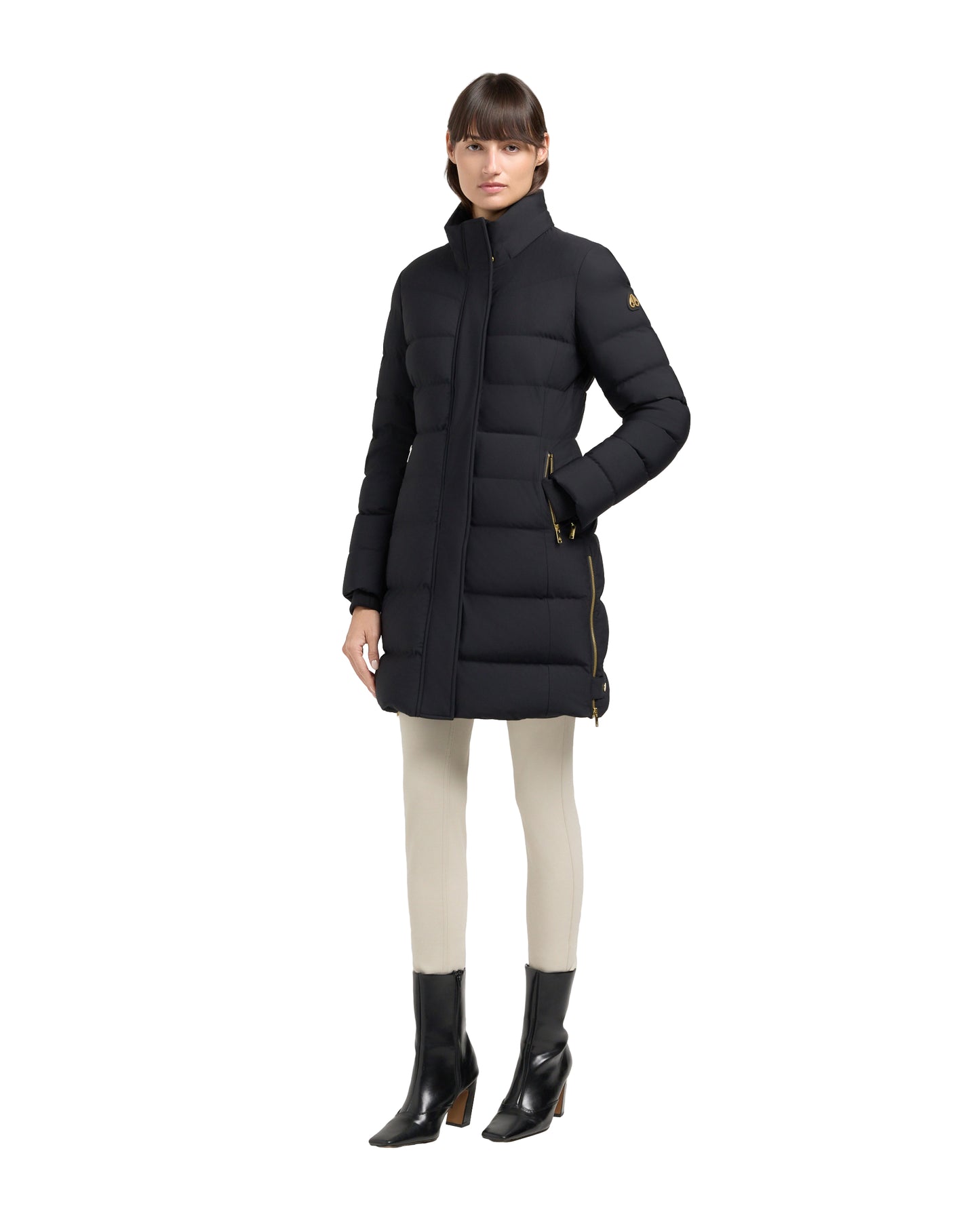 A woman is modeling a long, black puffer coat with boots.