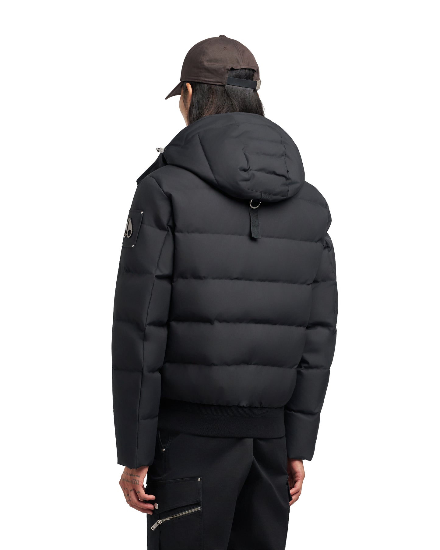 A person wearing a black puffy jacket and brown cap, facing away from the viewer.