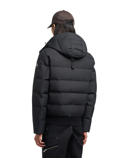 A person wearing a black puffy jacket and brown cap, facing away from the viewer.