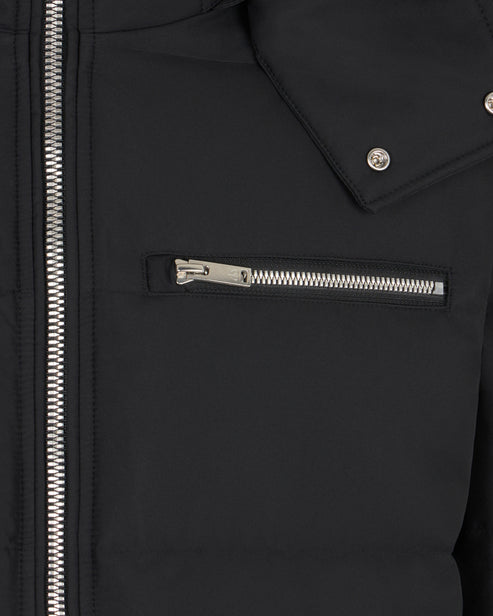 Close-up of a black jacket, focusing on a silver zipper detail on a chest pocket and the jacket's main zipper.