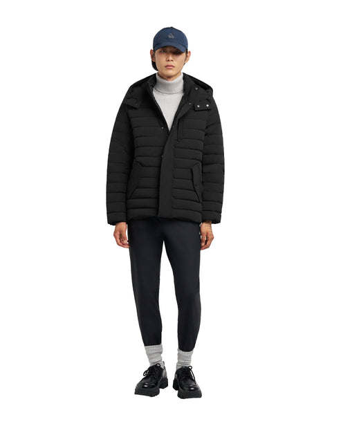 A person wearing a black puffer jacket, gray turtleneck, black pants and a blue cap.