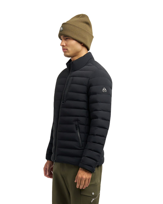 A man wearing a black puffer jacket and green beanie.