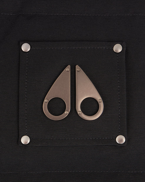 Close up of a black patch on clothing with two silver moose knuckle-shaped decorations attached with silver rivets.