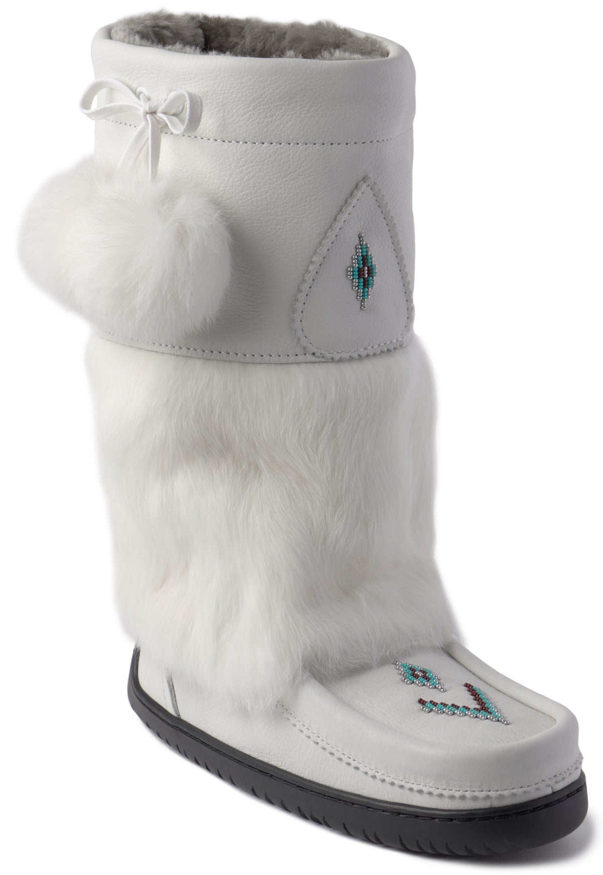 A tall white leather winter boot featuring thick white faux fur lining the shaft, a white pom-pom accent on the side near the cuff, a decorative bow, and small blue and black geometric beadwork details on the front of the ankle and toe, finished with a black rubber outsole.