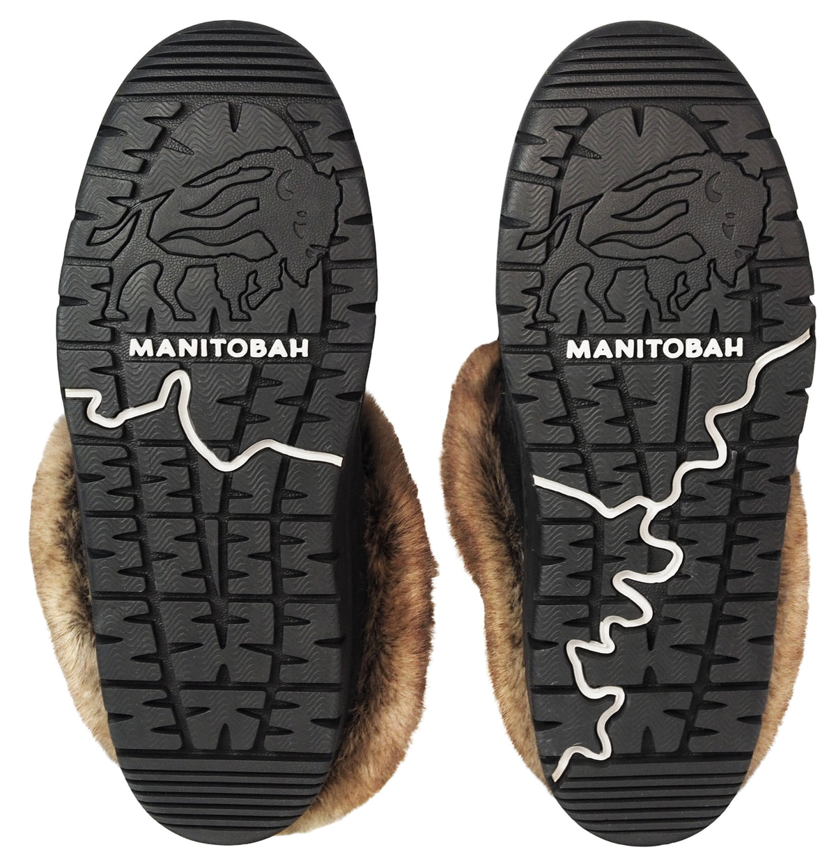 The black rubber outsoles of two winter boots, each featuring an embossed bison graphic, the word MANITOBAH in white text, and a decorative white line, with brown fur lining visible around the edges.