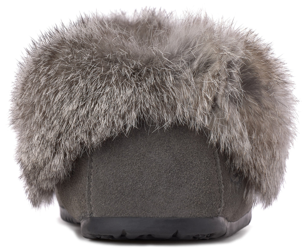 A close-up, back-view of a grey suede slipper lined with a thick band of grey faux fur, sitting on a dark, textured rubber sole.