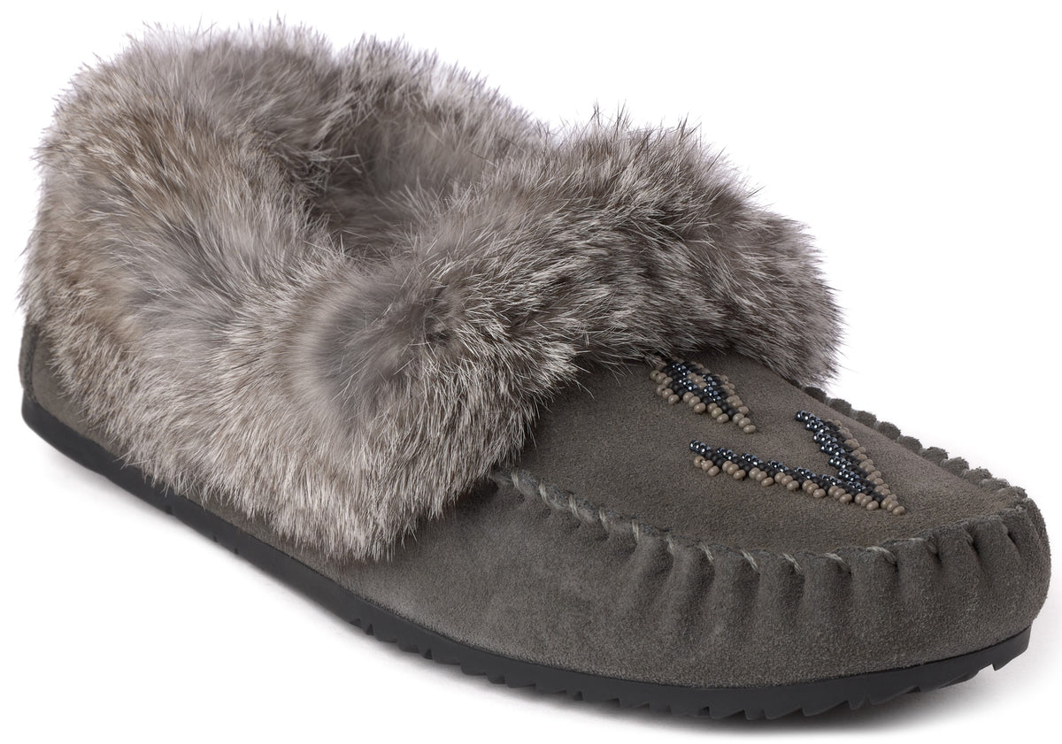 A gray suede moccasin-style slipper with a thick, plush gray faux fur cuff around the collar and a V-shaped pattern of small dark beads on the toe.