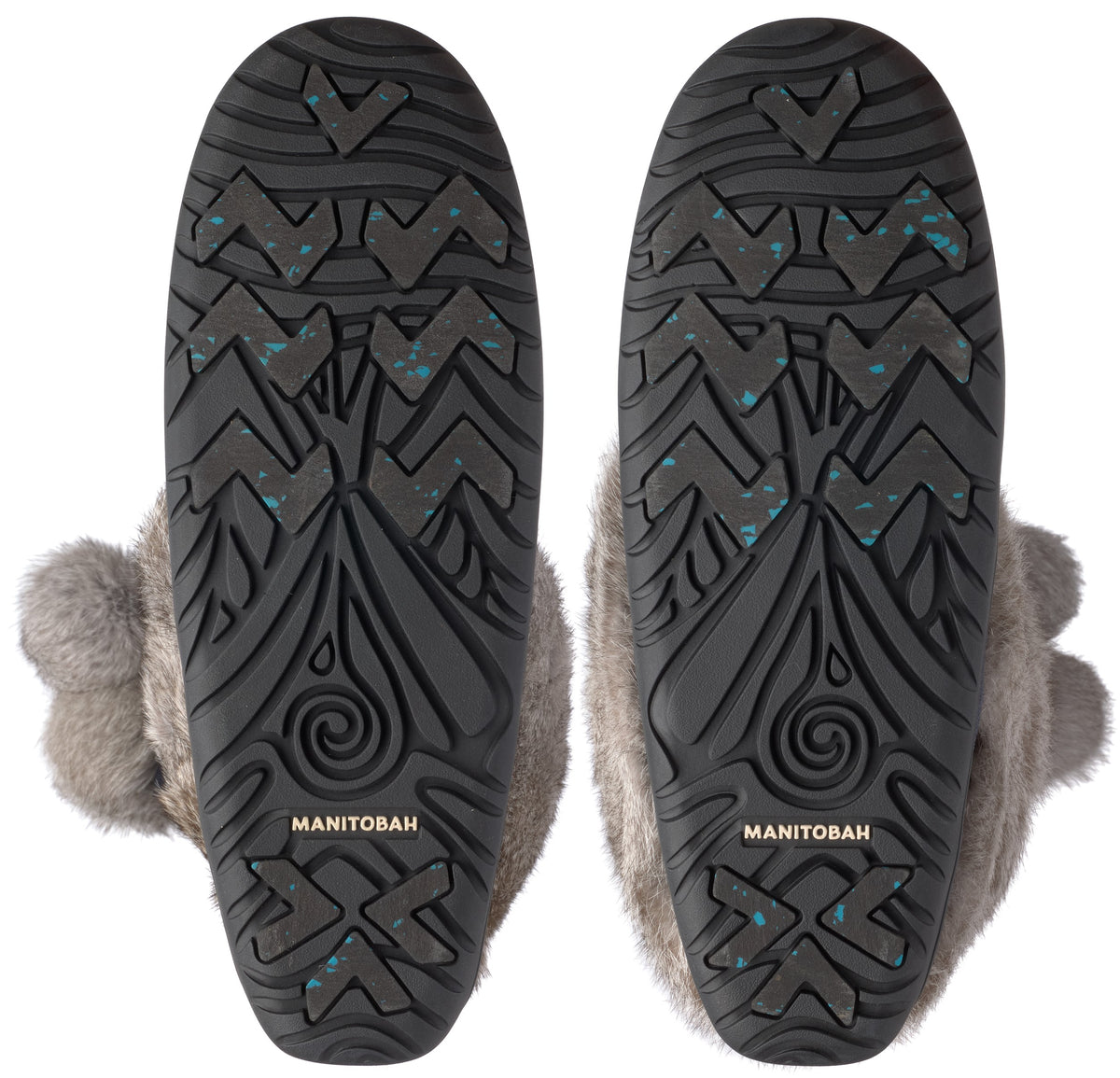 A pair of gray fur-lined slipper soles showing black rubber outsoles with a decorative geometric pattern, embossed Manitoba text, and small blue specks.