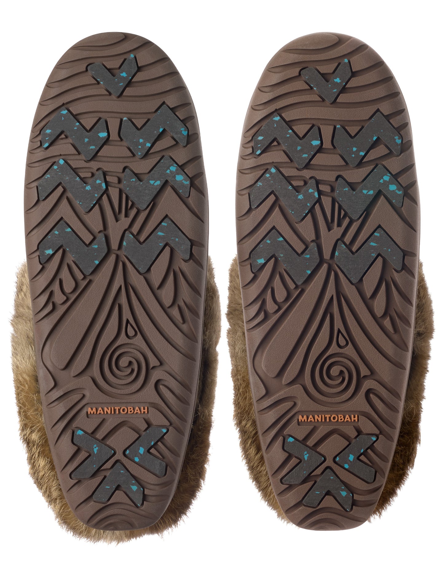 Two brown soles with visible treads and embedded teal pieces are attached to fur-covered shoes. One sole has the word "MANITOBAH" printed on it.