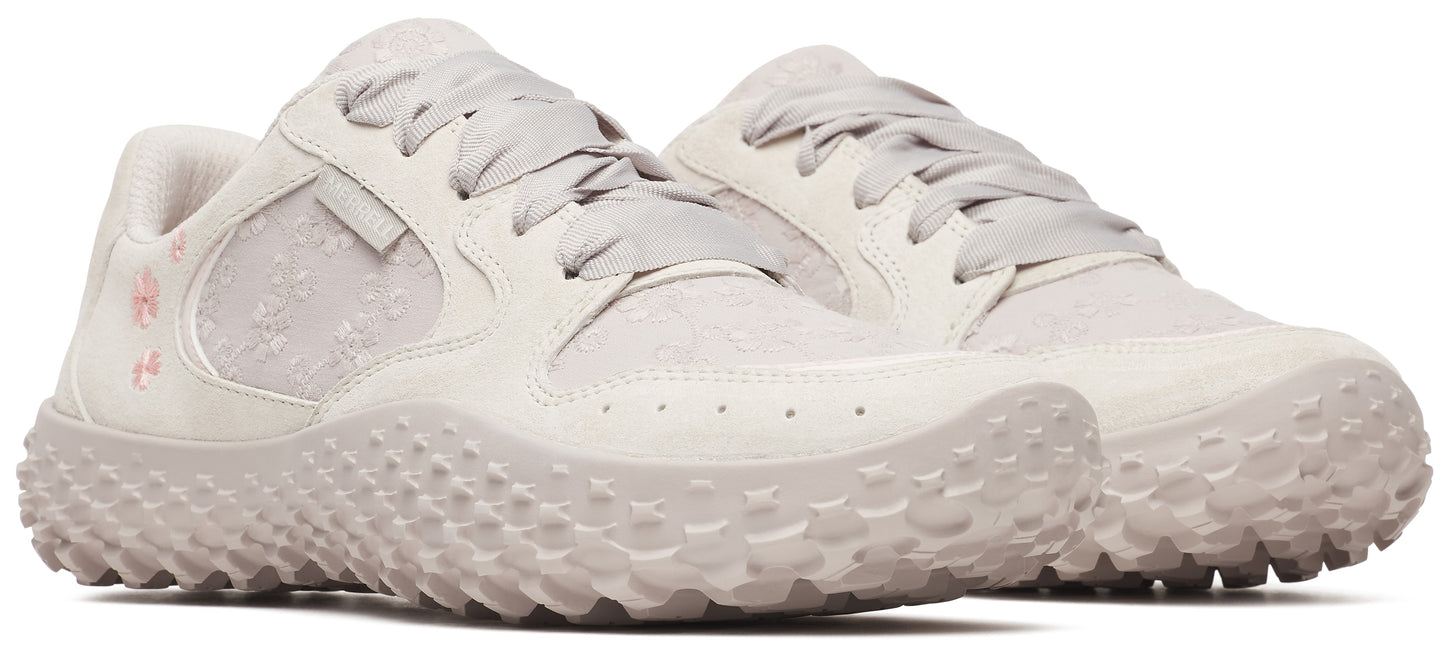 A pair of light-gray shoes with a unique studded sole and a floral pattern near the heel.