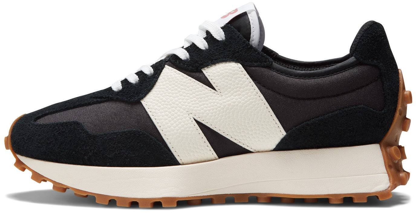 A New Balance 327 sneaker in a black, off-white, and gum colorway, featuring a black textile upper with black suede overlays, an oversized white leather N logo on the side, a thick off-white foam midsole, and a rugged gum-colored rubber outsole that extends up the heel.