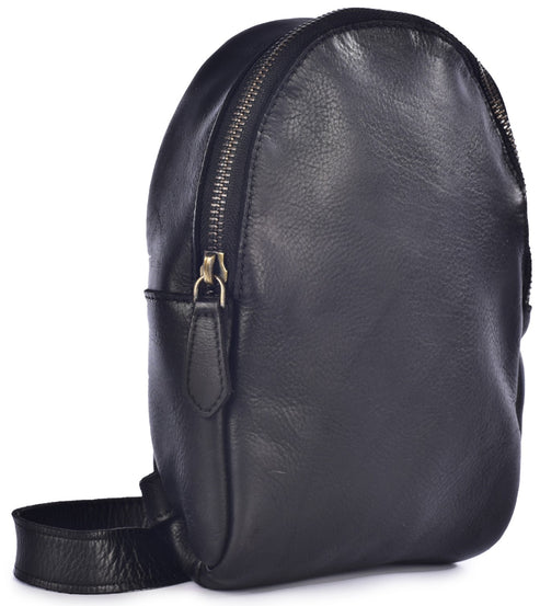 A minimalist, black leather, teardrop-shaped backpack standing upright, featuring a single prominent silver zipper along the top and side, and a simple black shoulder strap at the base.