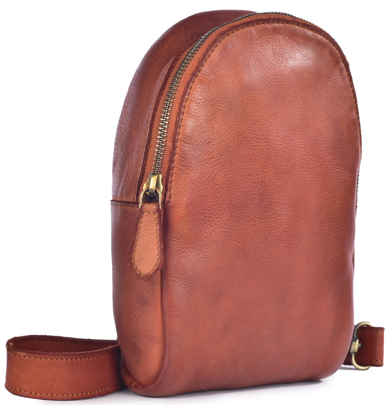 A minimalist, semi-oval shaped brown leather sling bag with a vertical zipper closure, a leather zipper pull, and a single adjustable shoulder strap against a white background.