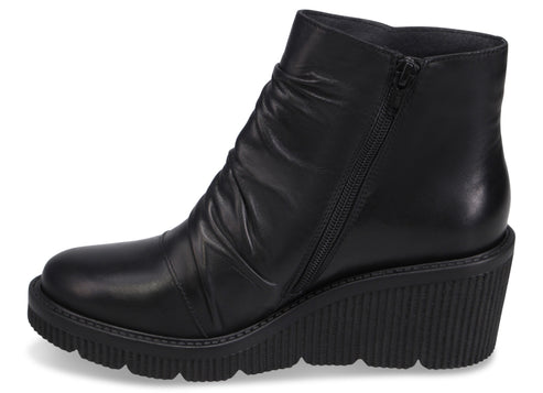 A black leather ankle boot with a side zipper, a ruched upper, and a thick, ridged wedge sole.