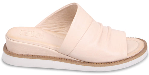 Beige leather slide sandal with wedge heel and white sole.