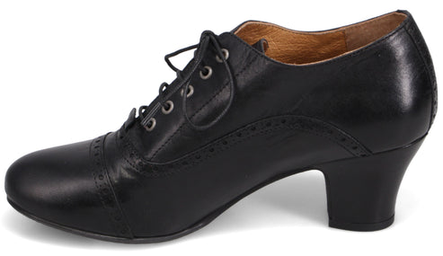 A black leather lace-up oxford shoe with a rounded toe and a low block heel, featuring decorative brogue-style perforations along the toe cap and side panels.