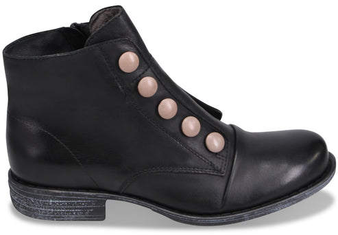 A black ankle boot with a rounded toe, a low stacked heel with a distressed finish, and a row of five large, round, pale-pink decorative buttons lining the side.
