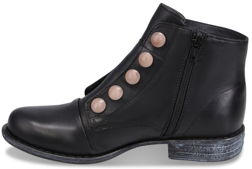 A black leather ankle boot with a rounded toe, a low distressed-look heel, a side zipper closure, and a decorative row of five pale pink circular buttons running diagonally up the instep.