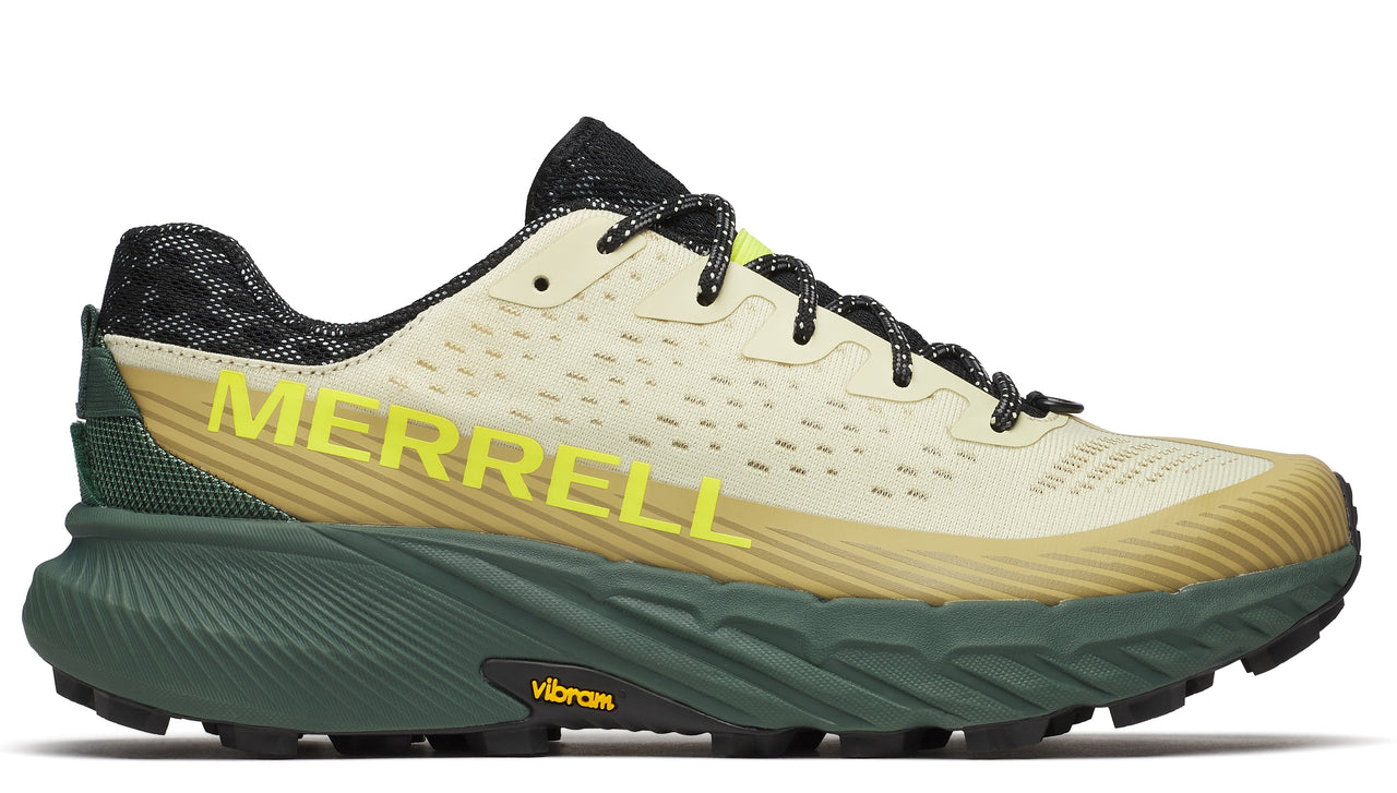A running shoe with a light beige upper, green textured sole, and yellow "MERRELL" lettering.