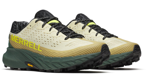 A pair of tan sneakers with yellow logo "MERRELL" and black laces, with a green and tan sole.