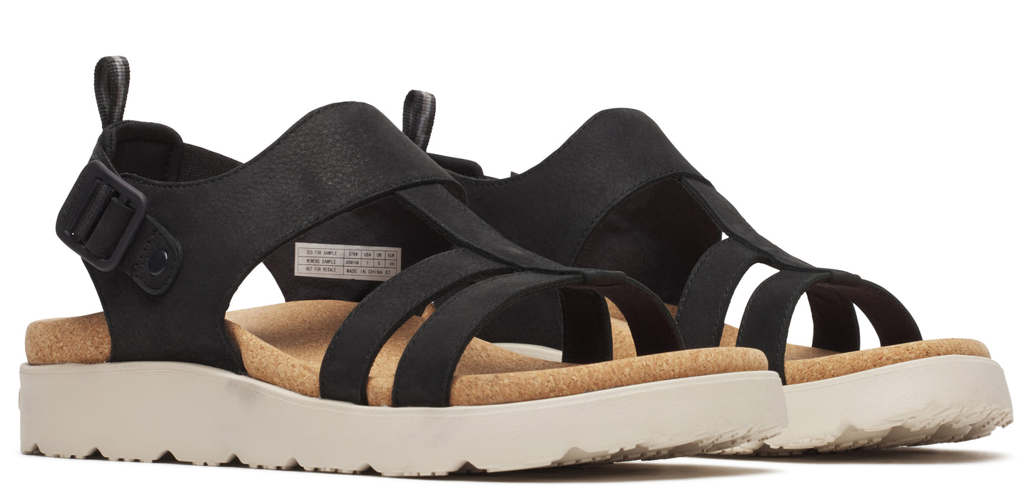A pair of black T-strap sandals with an adjustable buckle and a thick, white sole.
