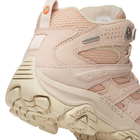 Close-up of a light pink hiking boot with visible Vibram and Merrell brand text.