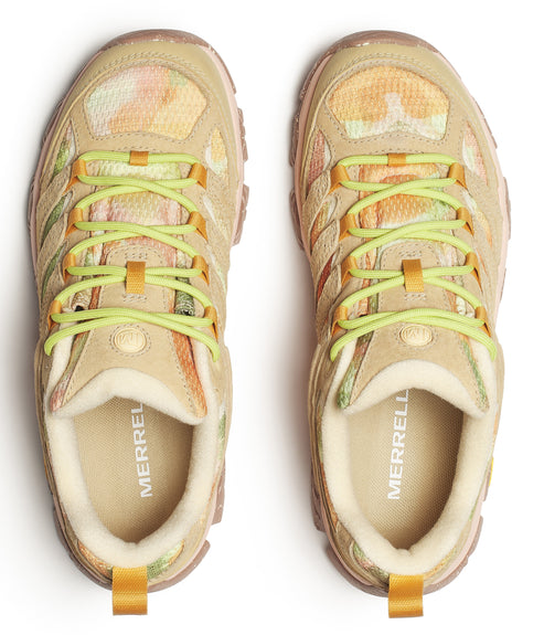 Top-down shot of two tan and orange trail running shoes with green laces; 'MERRELL' is printed on the insole.