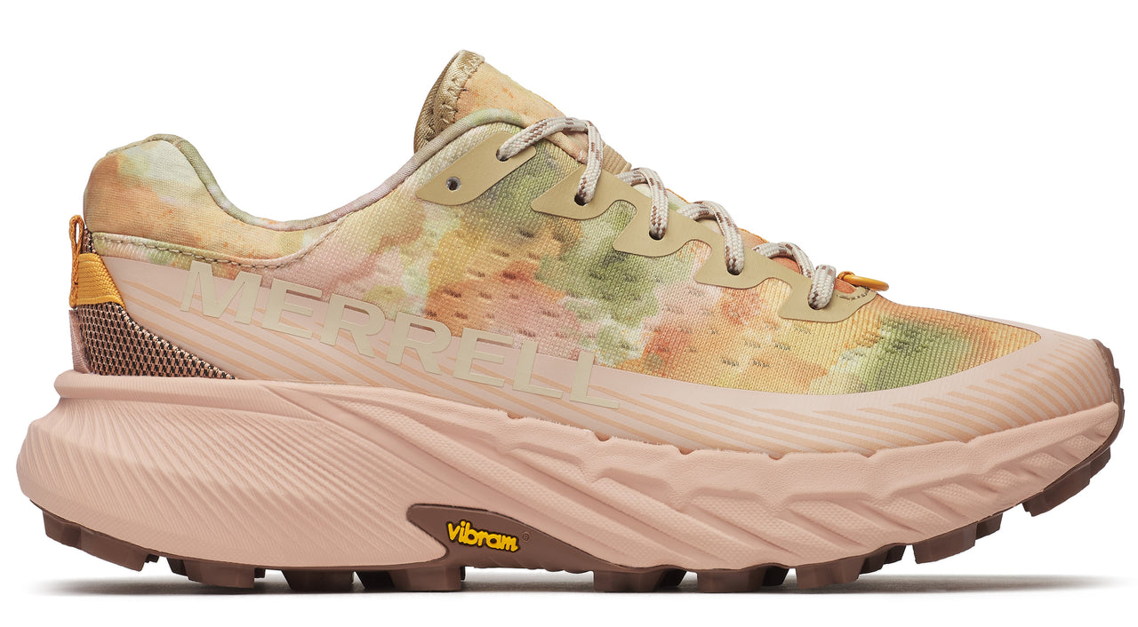 Side view of a trail running shoe with a patterned beige, green, and peach upper, beige midsole, and brown outsole with Vibram logo.