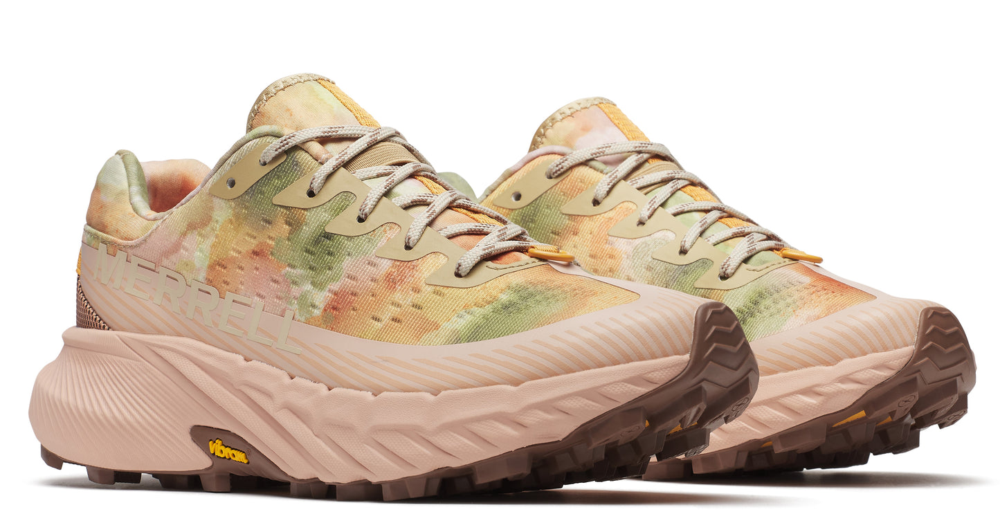 A pair of light beige running shoes with a yellow, orange and green dye-like pattern on the uppers, with brown lug soles.