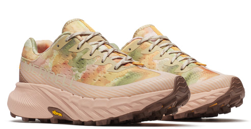 A pair of light beige running shoes with a yellow, orange and green dye-like pattern on the uppers, with brown lug soles.