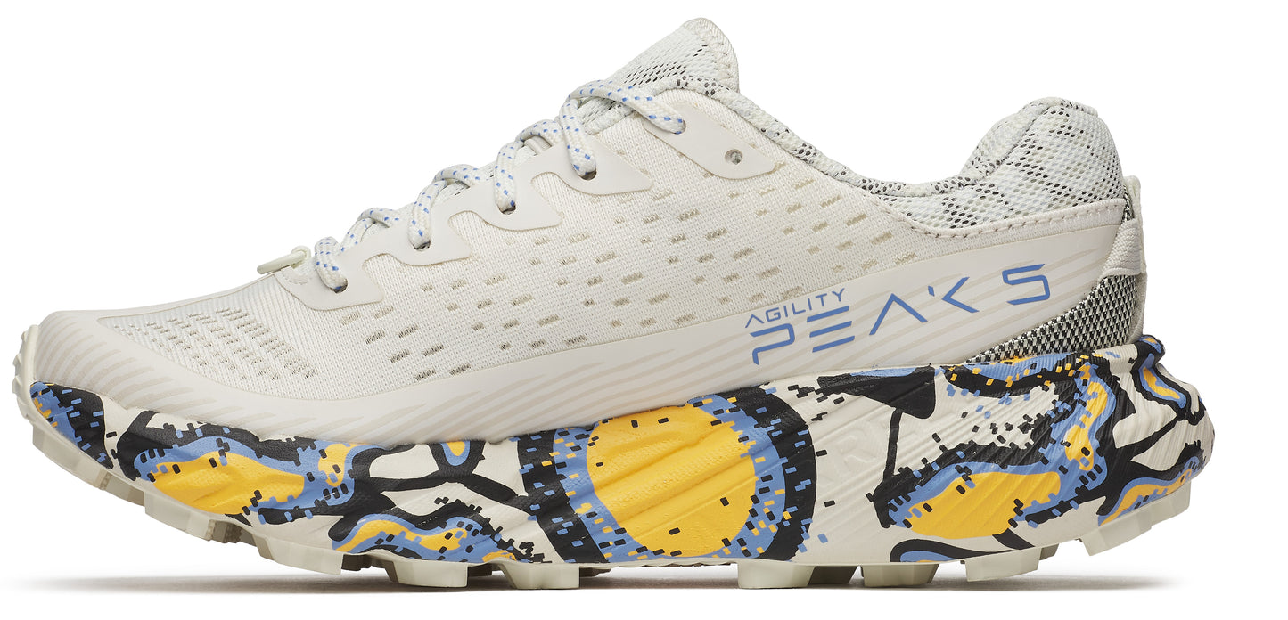 A shoe with white upper, laces, and sole with yellow and blue patterned designs.