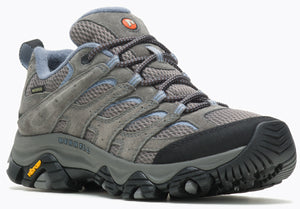 A gray hiking shoe with mesh panels, suede leather overlays, a black rubber toe cap, laces, a padded collar, a thick cushioned midsole with a yellow Vibram logo on the heel, and a rugged, multi-directional lugged outsole with the Merrell logo embossed on the side.