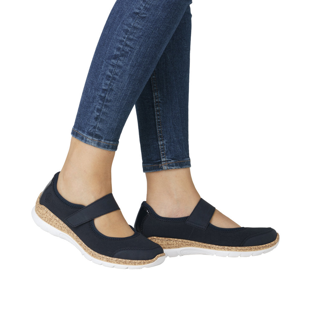 A person wearing navy casual Mary Jane shoes with a white sole and cork sidewall.