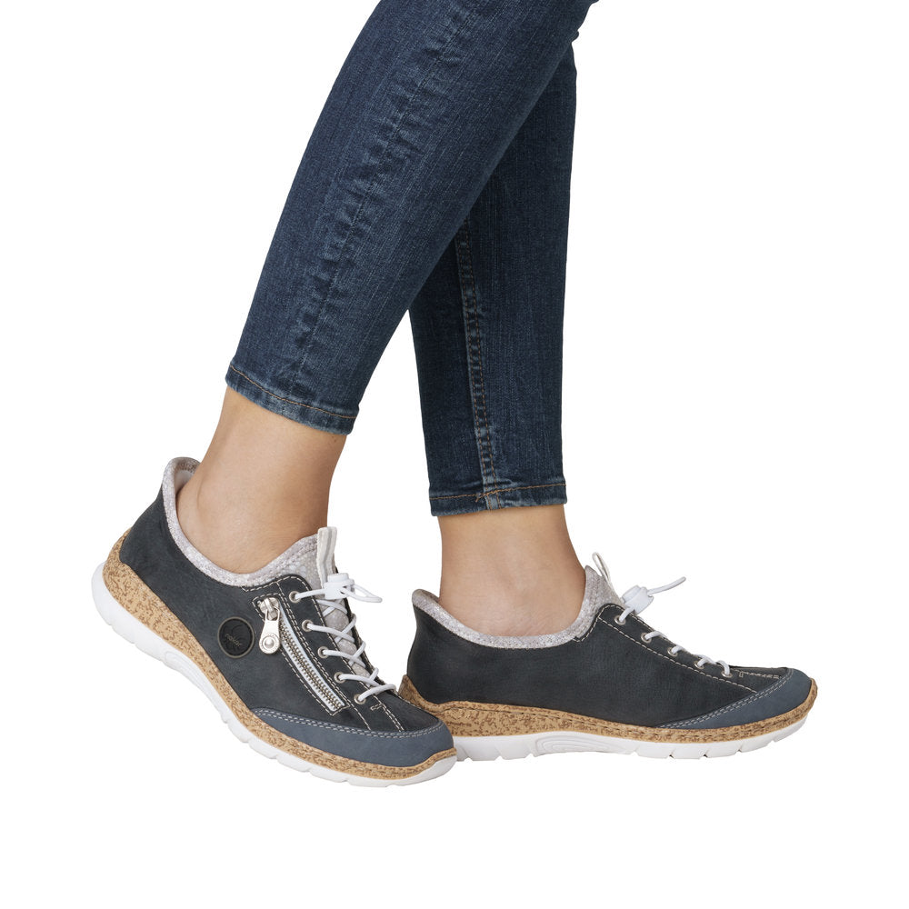 Low profile athletic style shoes are being worn with blue denim jeans.