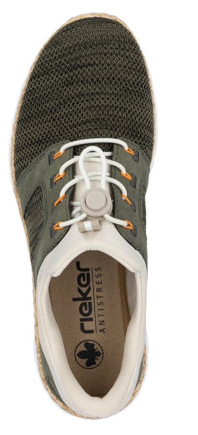 A closeup of a knitted light olive green shoe with white laces and a tan interior.